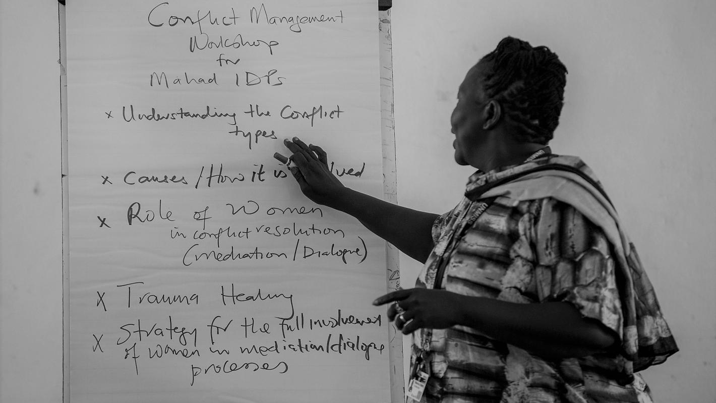 UNMISS Civil Affairs works in 10 field offices and two team sites across South Sudan to provide a link between the Mission, local authorities and communities to manage conflict, address social cohesion issues, and garner support for reconciliation initiatives between various conflicted communities. A black and white photo of a woman standing at a flipchart easel.